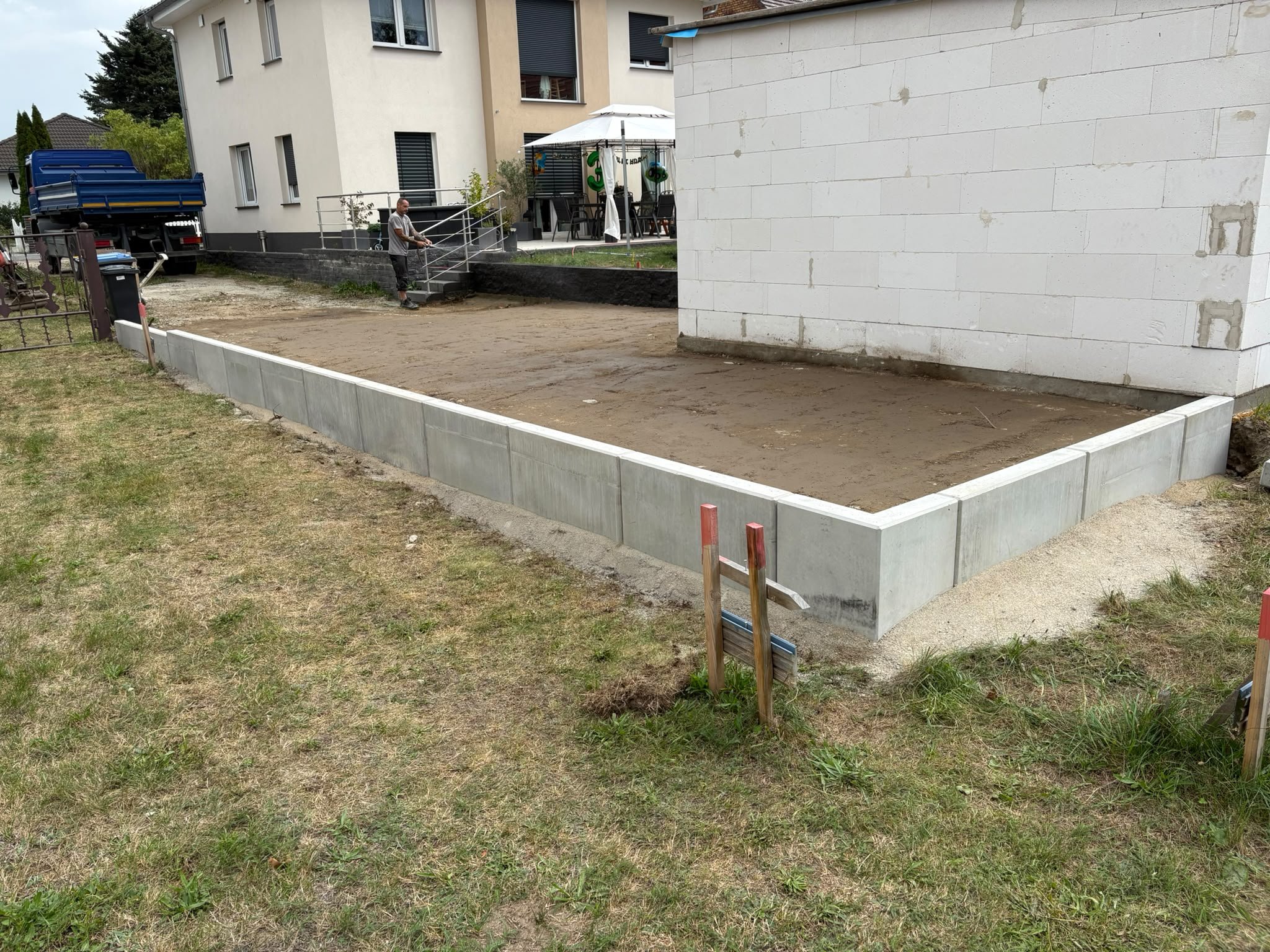 Vorbereitete Fläche mit Winkelsteinen als Einfassung neben einem Neubau