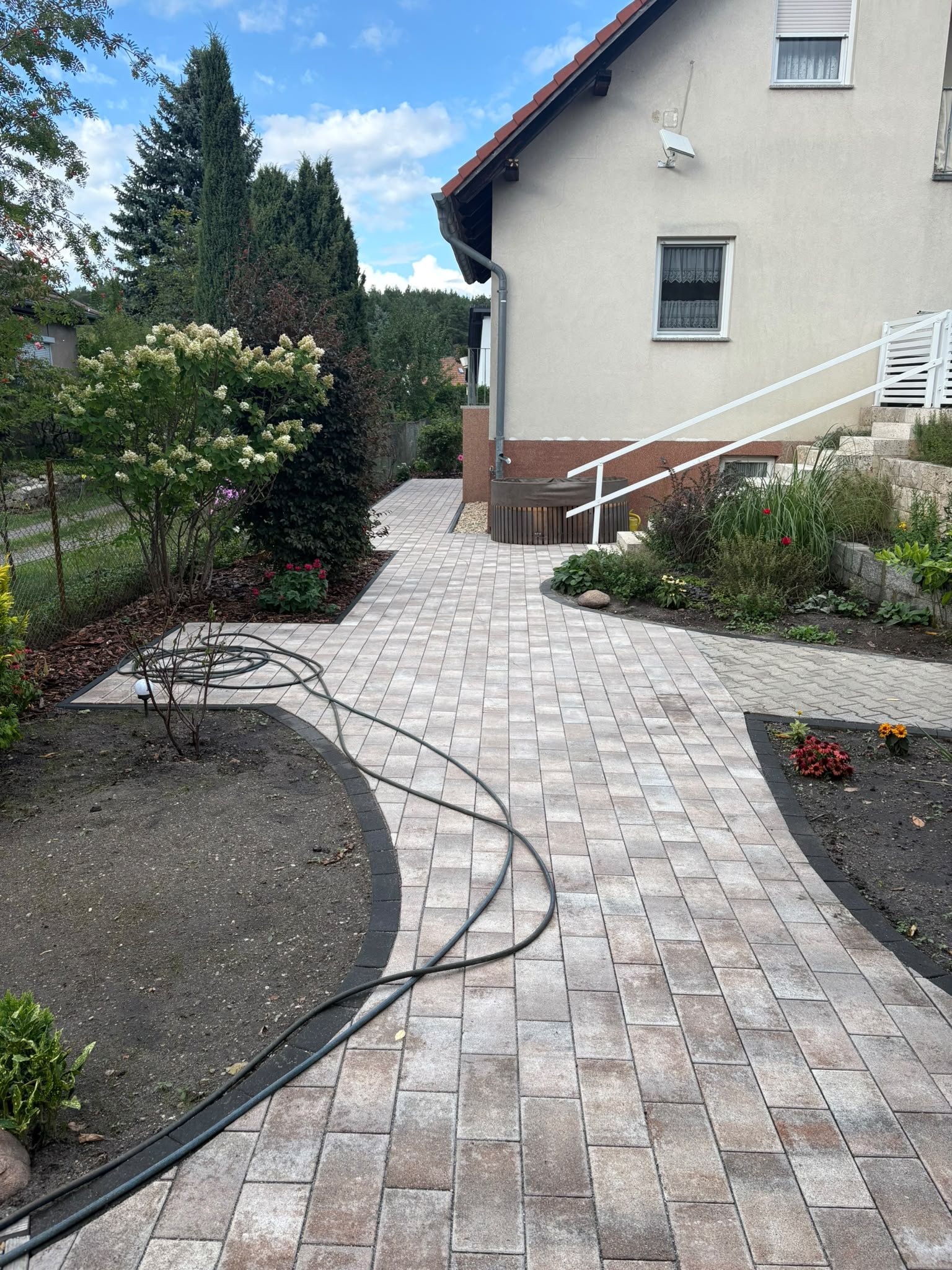 Neuer Gartenweg aus Rechteckpflaster zwischen frisch angelegten Beeten