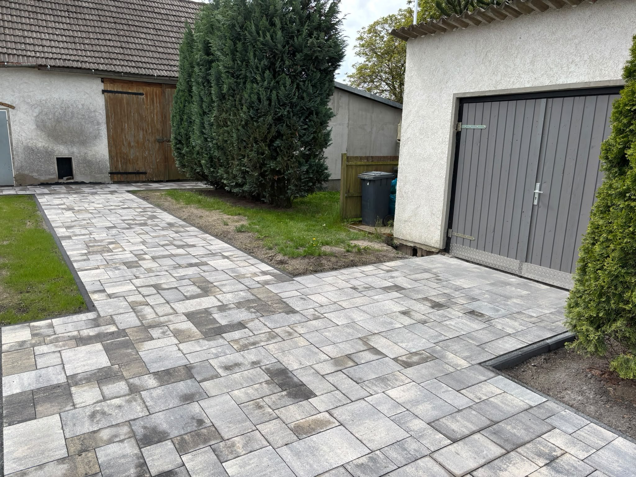 Gepflasterter Hof in Grautönen vor einer Garage