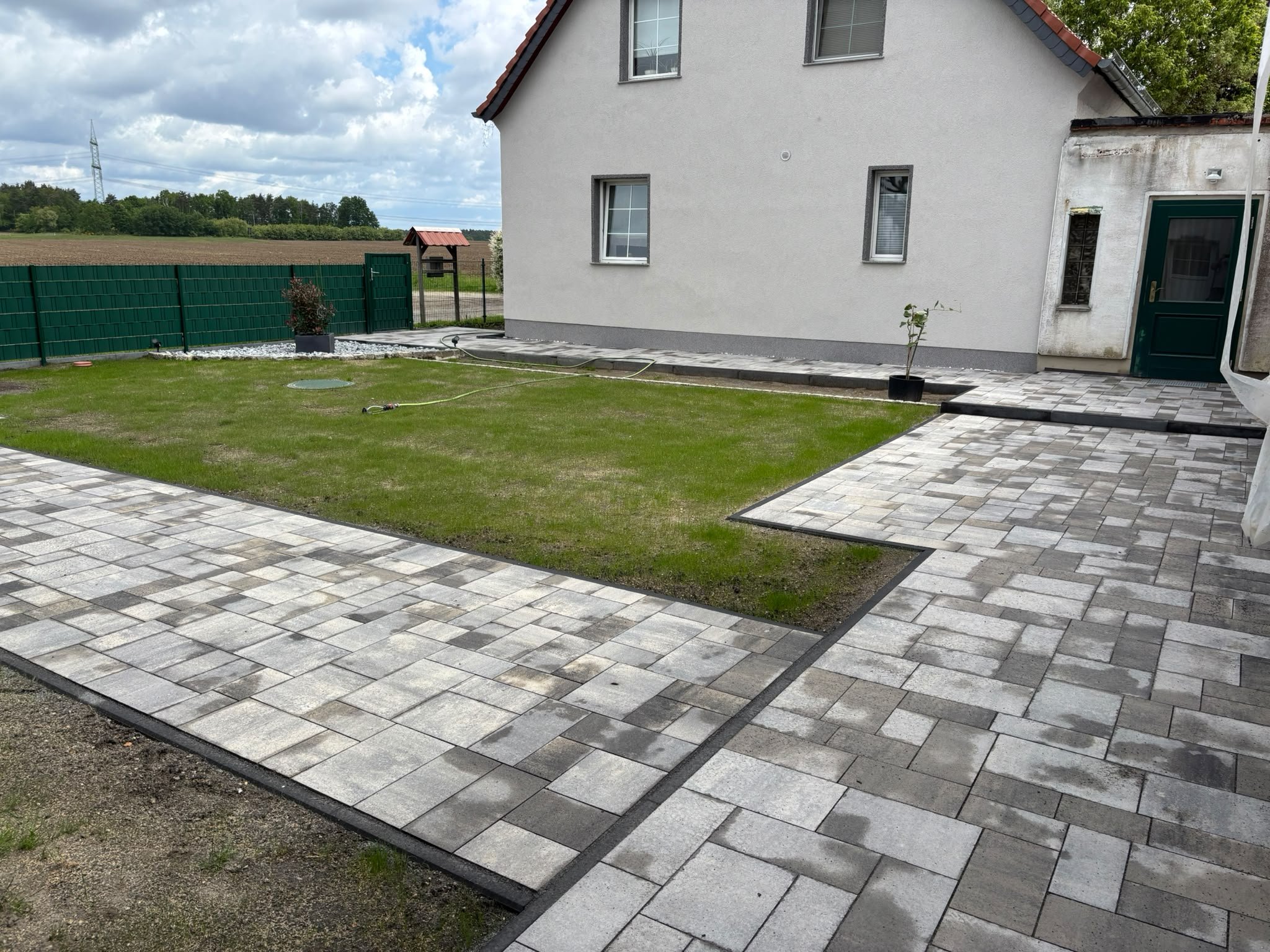 Hof mit frisch angelegtem Rasen und neuen Pflasterflächen an einem Wohnhaus