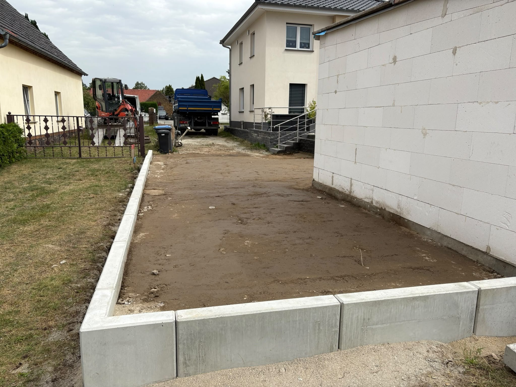 Ausgehobene und eingefasste Fläche neben einem neuen Wohnhaus