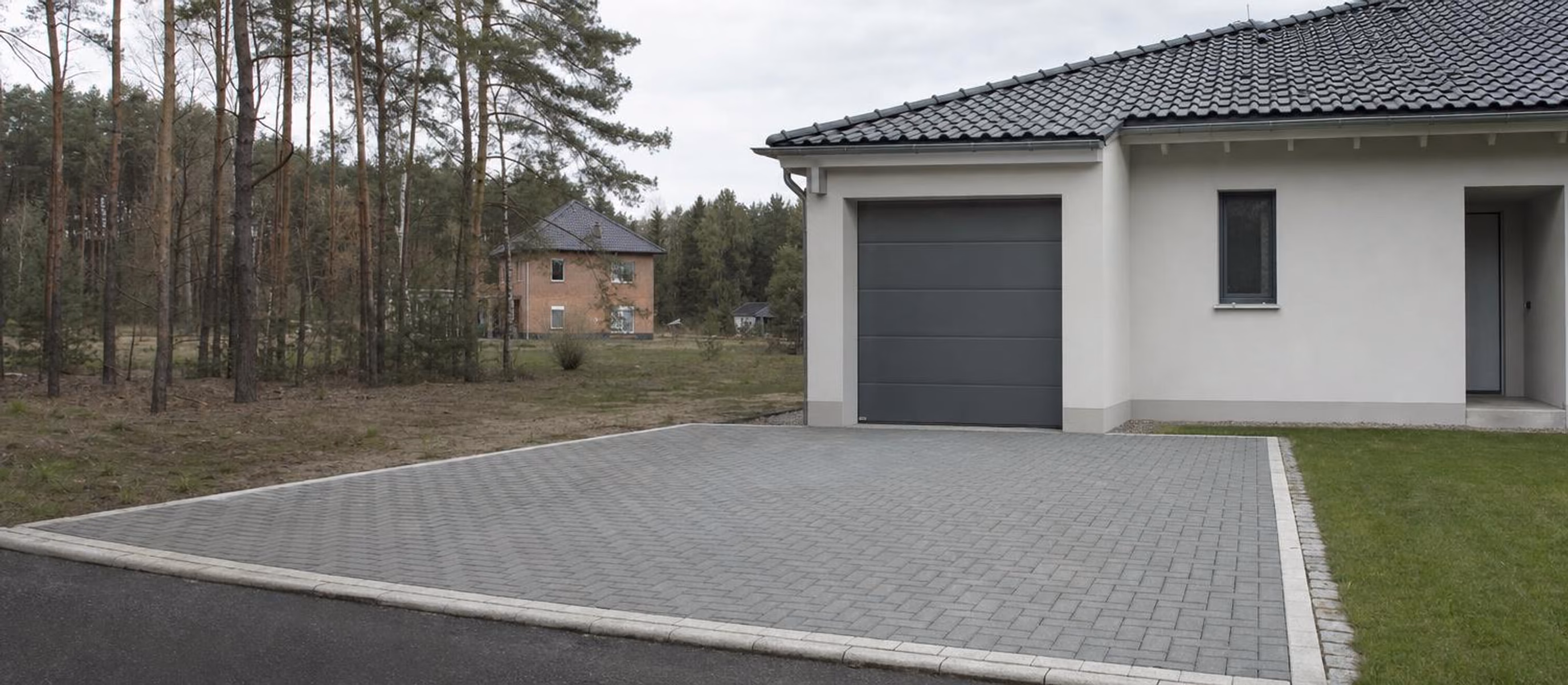 Gepflasterte Einfahrt vor einer Garage mit sauberen Randsteinen